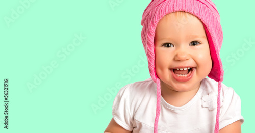 Photo: Funny happy baby girl in a pink winter knitted hat laughing Funny happy baby girl in a pink winter knitted hat laughing
