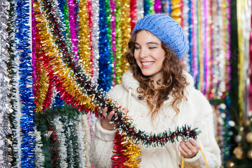 Photo: Young Woman Choosing Tinsels At Store Young Woman Choosing Tinsels At Store