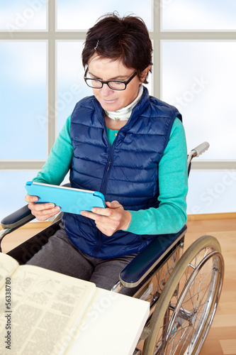 Photo: Woman with Tablet PC's in a wheelchair at the table Woman with Tablet PC's in a wheelchair at the table