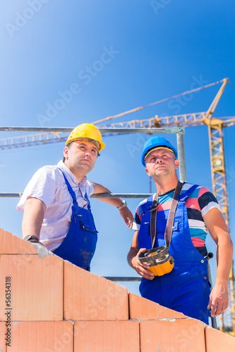 Photo: Construction site workers building house with crane Construction site workers building house with crane