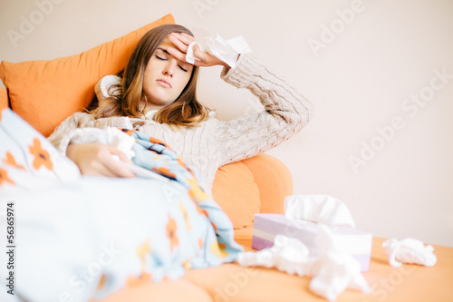 Photo: Young woman with cold / flu lying on the couch Young woman with cold / flu lying on the couch