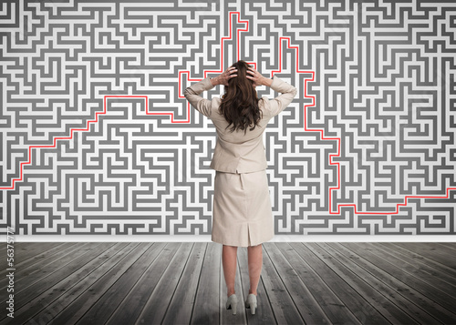 Photo: Puzzled businesswoman looking at a maze Puzzled businesswoman looking at a maze