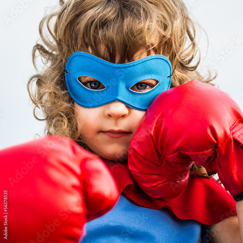 Photo: Superhero kid wearing boxing gloves. Girl power and feminism Superhero kid wearing boxing gloves. Girl power and feminism