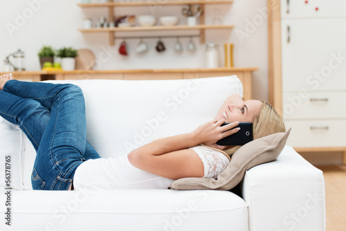 Photo: frau liegt auf dem sofa und telefoniert mit ihrem handy frau liegt auf dem sofa und telefoniert mit ihrem handy