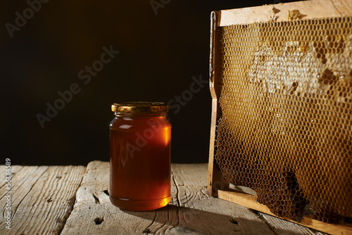 Photo: honeycomb with fresh honey in a vase on wooden table. honeycomb with fresh honey in a vase on wooden table.