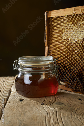 Photo: honeycomb with fresh honey in a vase on wooden table. honeycomb with fresh honey in a vase on wooden table.
