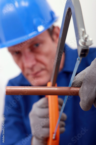Photo: Man sawing copper pipe Man sawing copper pipe
