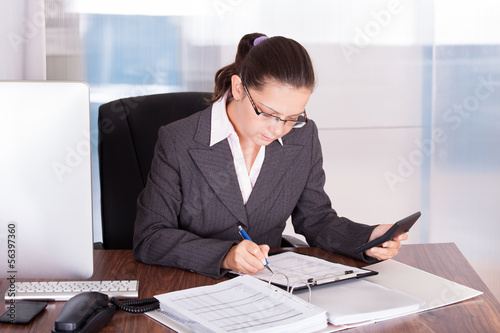 Photo: Happy young woman calculating finances Happy young woman calculating finances