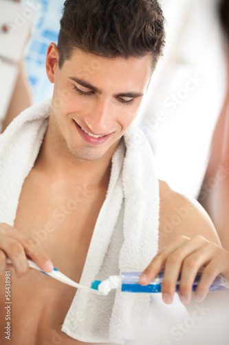 Photo: Young man squeezes toothpaste on the brush Young man squeezes toothpaste on the brush