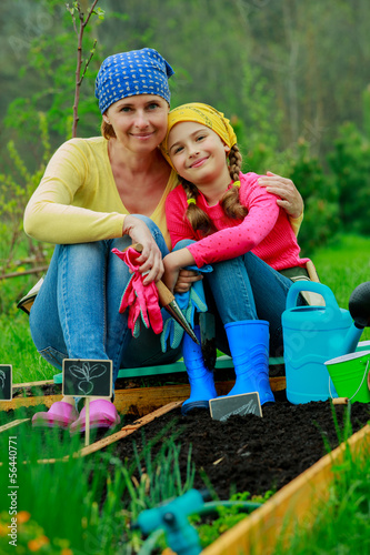 Photo: Gardening - girl helping mother in the garden Gardening - girl helping mother in the garden