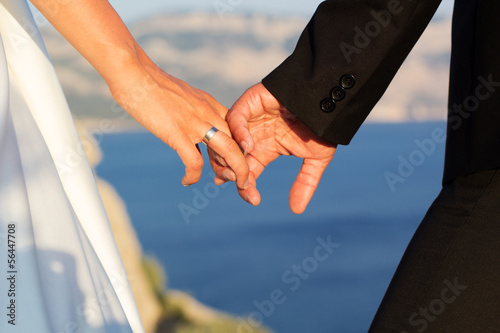 Photo: Wedding couple holding hands on sea background Wedding couple holding hands on sea background