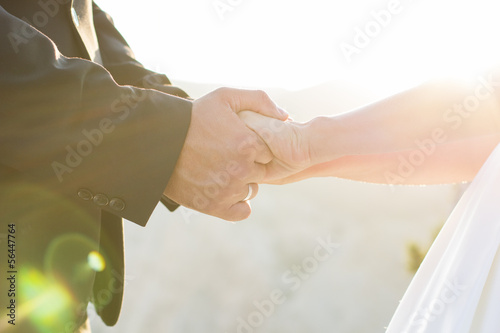 Photo: Wedding couple holding hands on sunset background Wedding couple holding hands on sunset background