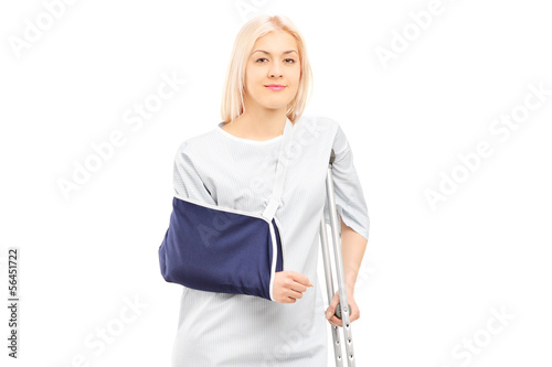 Photo: Blond female patient in hospital gown with broken arm and crutch Blond female patient in hospital gown with broken arm and crutch