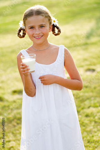 Photo: Healthy kid - lovely girl drinking fresh milk outdoors Healthy kid - lovely girl drinking fresh milk outdoors