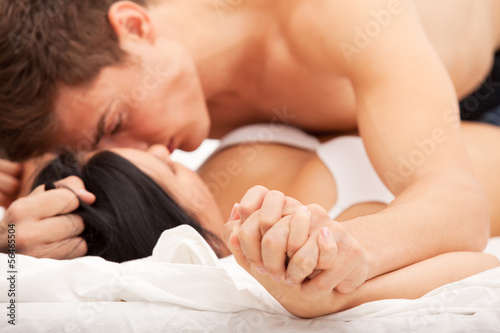 Photo: Sexy young couple kissing and playing in bed. Sexy young couple kissing and playing in bed.