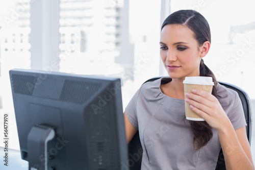 Photo: Attractive businesswoman holding coffee and working Attractive businesswoman holding coffee and working