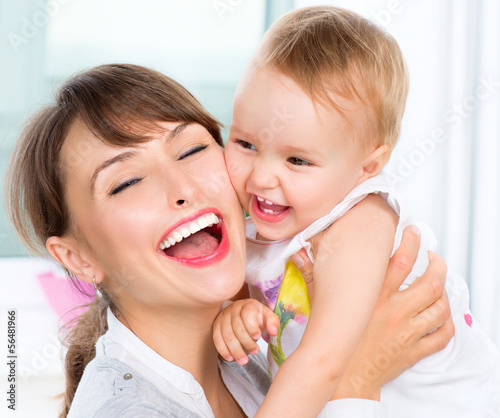 Photo: Happy Smiling Mother and Baby kissing and hugging at Home Happy Smiling Mother and Baby kissing and hugging at Home