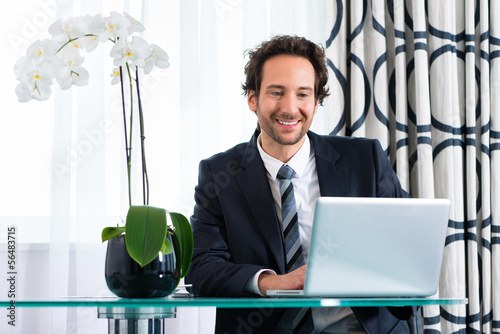 Photo: businessman in hotel working on laptop businessman in hotel working on laptop