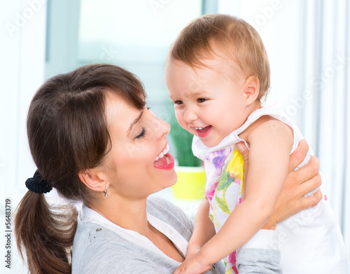 Photo: Happy Smiling Mother and Baby kissing and hugging at Home Happy Smiling Mother and Baby kissing and hugging at Home