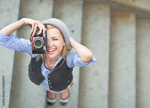 Photo: Happy hipster girl making photo with retro camera on city street Happy hipster girl making photo with retro camera on city street