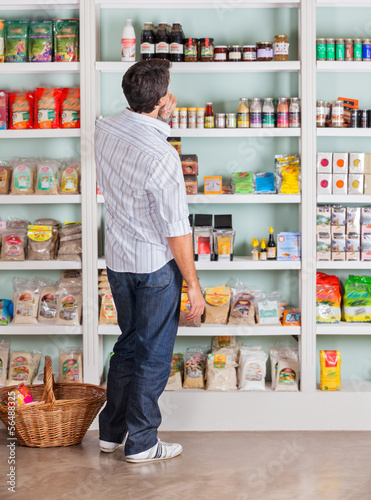 Photo: Thoughtful Man Choosing Products In Supermarket Thoughtful Man Choosing Products In Supermarket