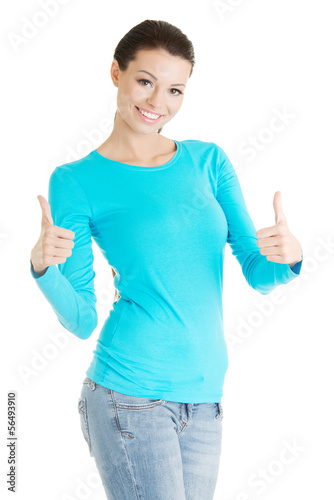 Photo: Beautiful young woman gesturing thumbs up. Beautiful young woman gesturing thumbs up.