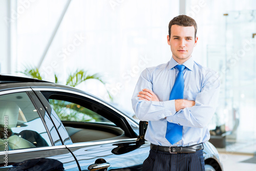Photo: dealer stands near a new car in the showroom dealer stands near a new car in the showroom