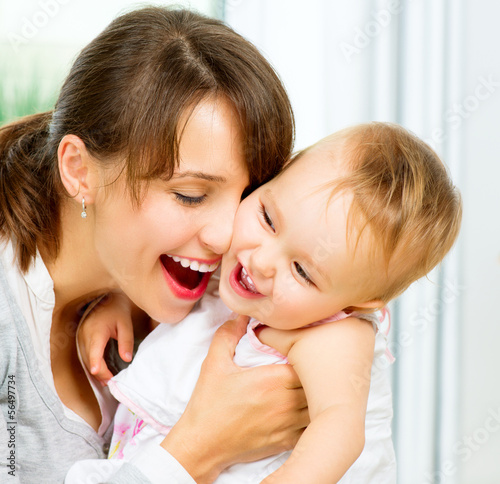 Photo: Happy Smiling Mother and Baby kissing and hugging at Home Happy Smiling Mother and Baby kissing and hugging at Home