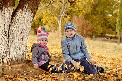 Photo: brother and sister playing leaves in park brother and sister playing leaves in park