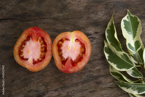 Photo: A Half of Tomato on the Wooden Table A Half of Tomato on the Wooden Table