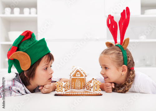 Photo: Kids with funny christmas hats and gingerbread house Kids with funny christmas hats and gingerbread house