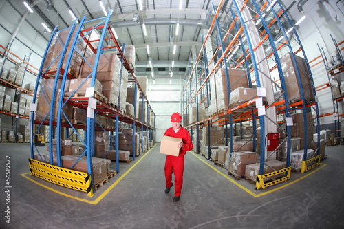 Photo: worker in red uniform with box in warehouse in fish-eye lens worker in red uniform with box in warehouse in fish-eye lens
