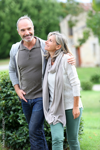 Photo: Cheerful mature couple walking in garden Cheerful mature couple walking in garden