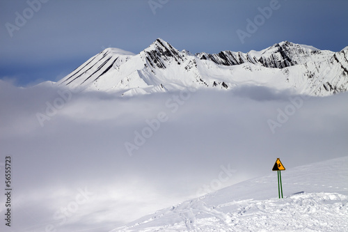 Photo: Warning sing on ski slope and mountains in fog Warning sing on ski slope and mountains in fog