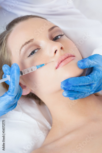 Photo: Surgeon making injection above lips on pretty woman lying Surgeon making injection above lips on pretty woman lying