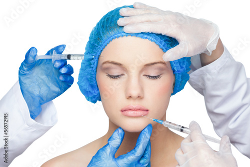 Photo: Surgeons making injection on calm blonde Surgeons making injection on calm blonde