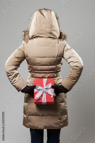 Photo: Woman with a Christmas gift behind her back Woman with a Christmas gift behind her back