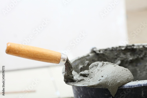 Photo: Dirty trowel and bucket on building site. Renovation at home Dirty trowel and bucket on building site. Renovation at home