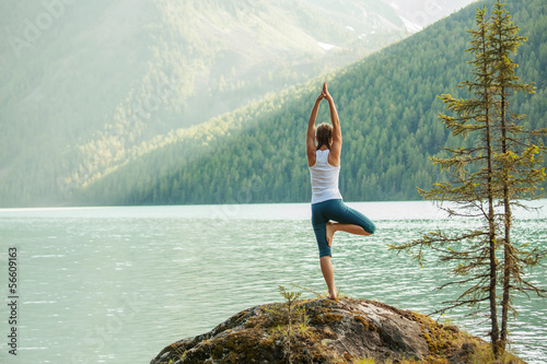 Photo: Young woman is practicing yoga at mountain lake Young woman is practicing yoga at mountain lake