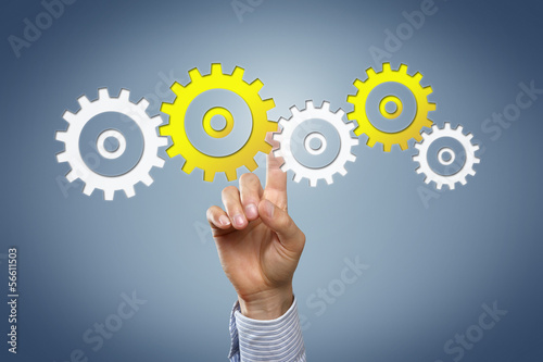 Photo: Hand touching cogwheels Hand touching cogwheels