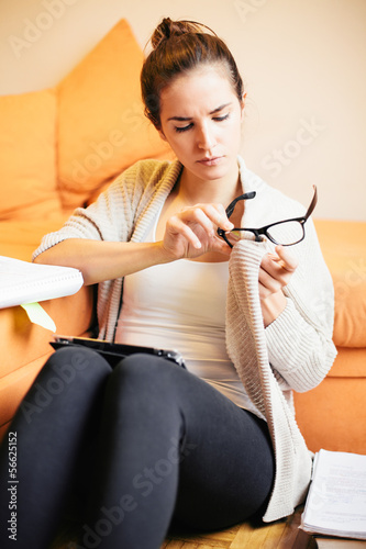 Photo: Young woman cleaning glasses and studying Young woman cleaning glasses and studying