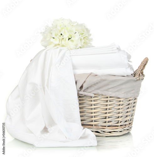 Photo: Bedding sheets in wicker basket isolated on white Bedding sheets in wicker basket isolated on white