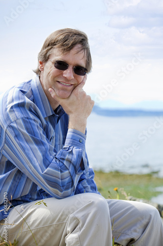 Photo: Handsome Causcasian man in forties relaxing by lake side Handsome Causcasian man in forties relaxing by lake side