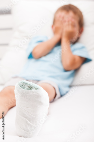 Photo: Little child boy with plaster bandage on leg heel fracture or br Little child boy with plaster bandage on leg heel fracture or br
