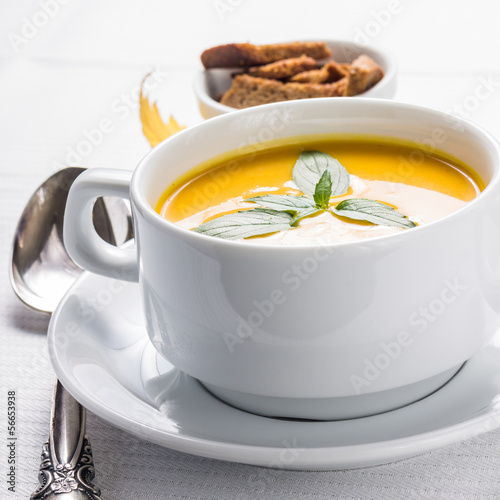 Photo: Pumpkin cream-soup in white bowl with silver spoon Pumpkin cream-soup in white bowl with silver spoon