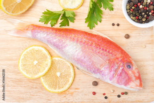 Photo: fresh surmullet, lemon and spices on a wooden board fresh surmullet, lemon and spices on a wooden board