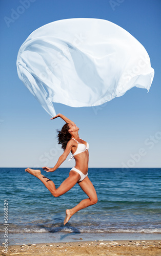 Photo: Sexy athletic brunette jumping on the beach. Sexy athletic brunette jumping on the beach.
