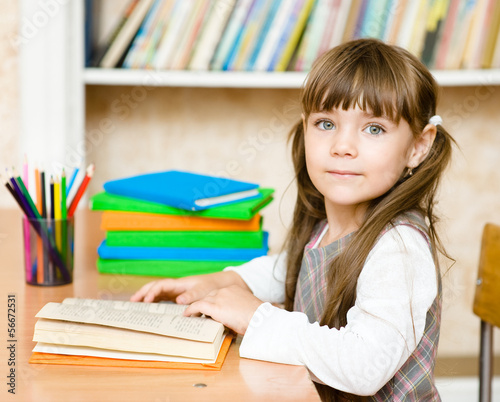 Photo: Young schoolgirl reading a book. looking at camera Young schoolgirl reading a book. looking at camera