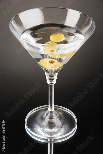 Photo: Martini with green olives on grey background Martini with green olives on grey background