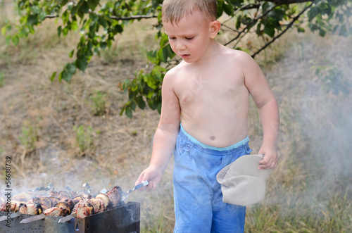 Photo: Little boy turning kebabs over the fire Little boy turning kebabs over the fire